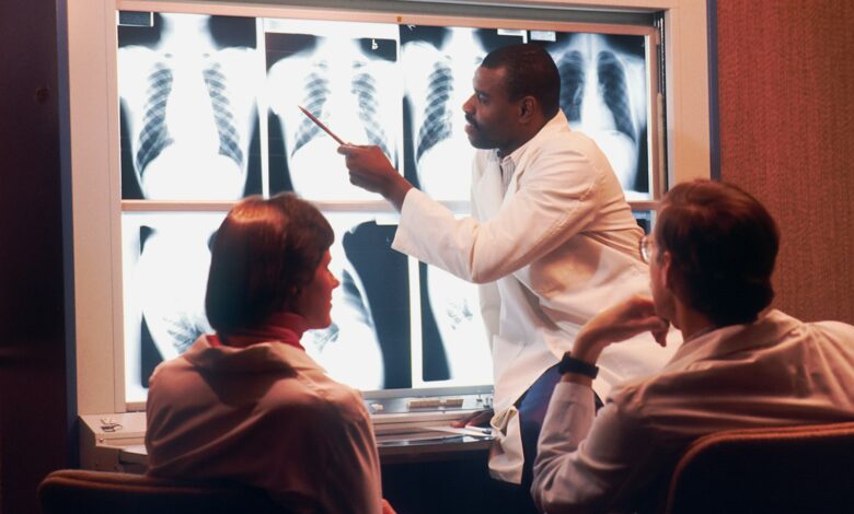 a man in a white lab coat pointing to an x - ray